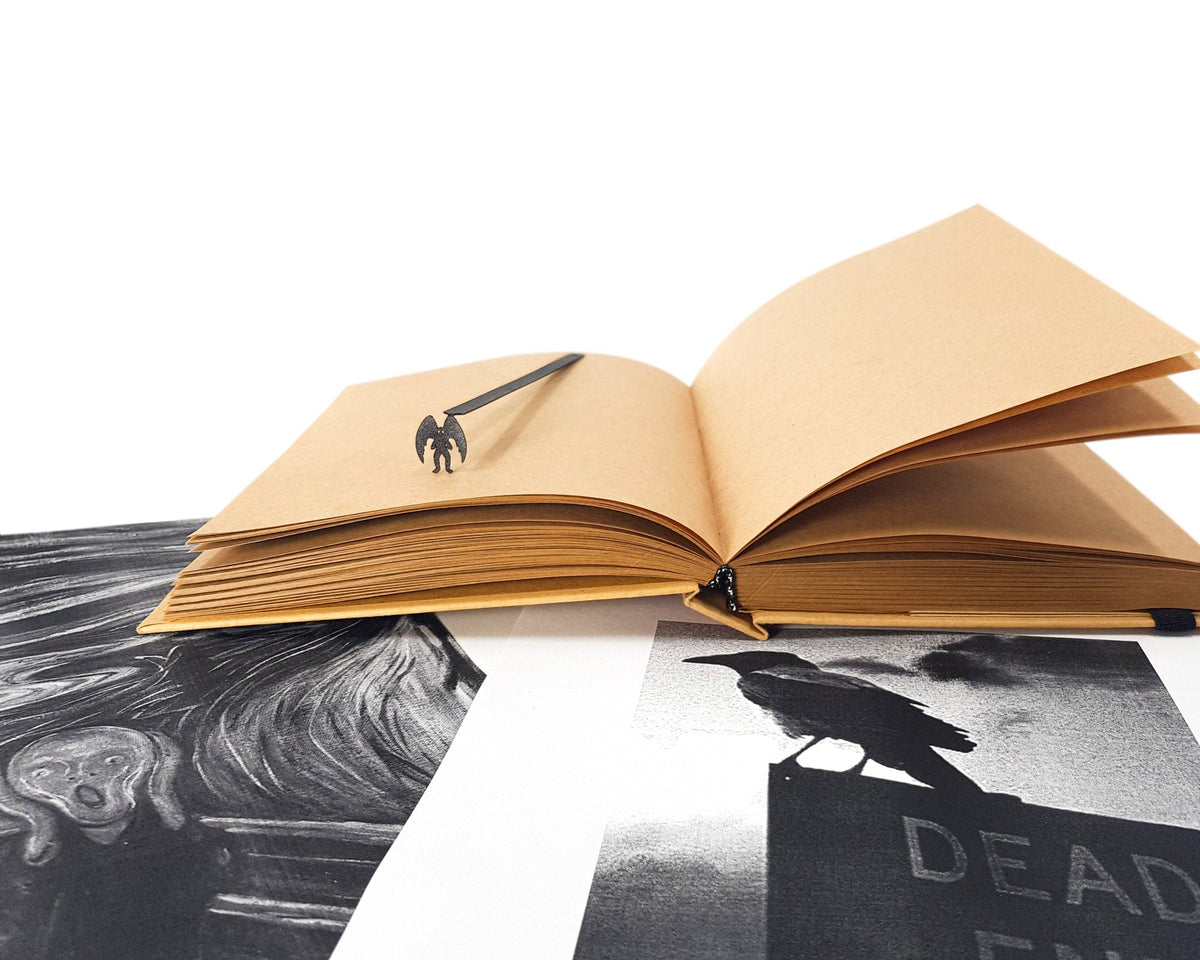 Mothman metal bookmark resting on the pages of an open book