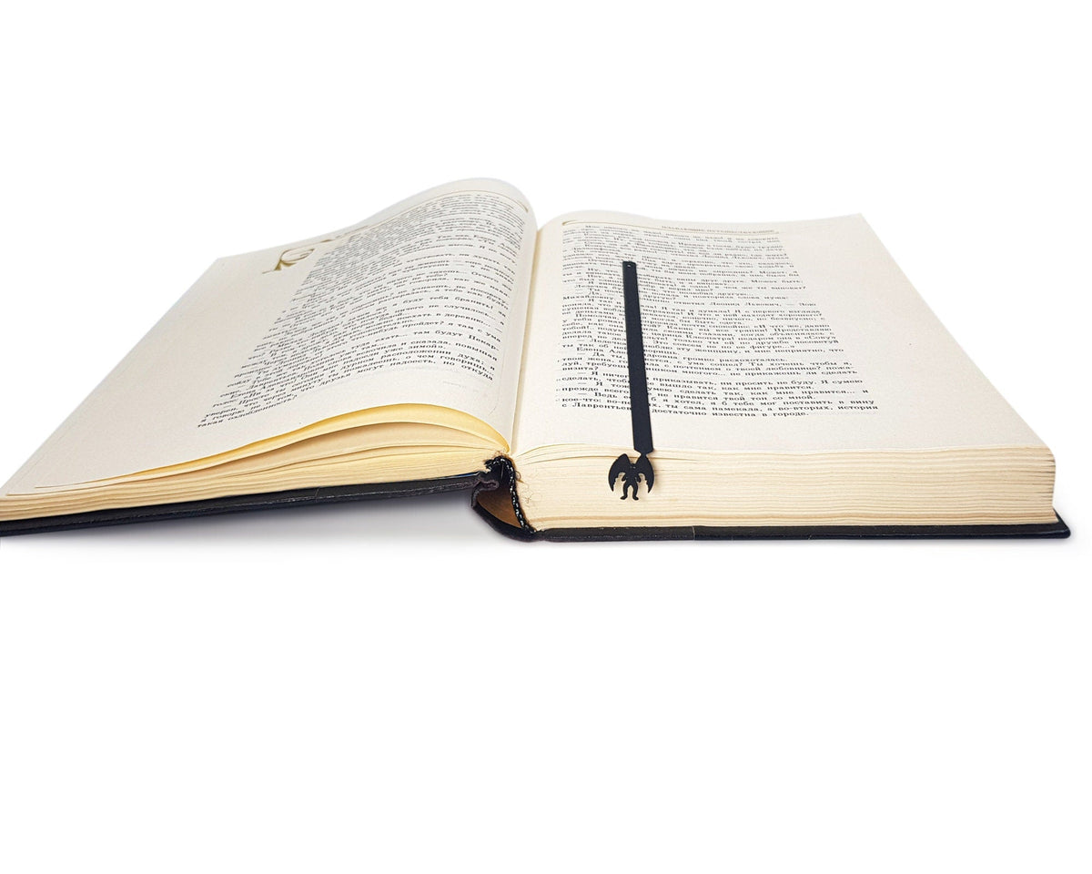 Mothman metal bookmark lying across the pages of an open book