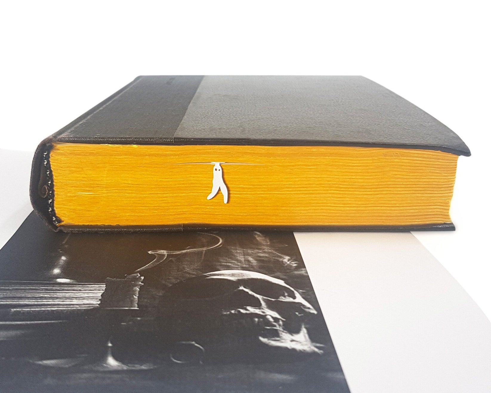 Nightcrawler metal bookmark in white in a closed book, only its top showing above the pages