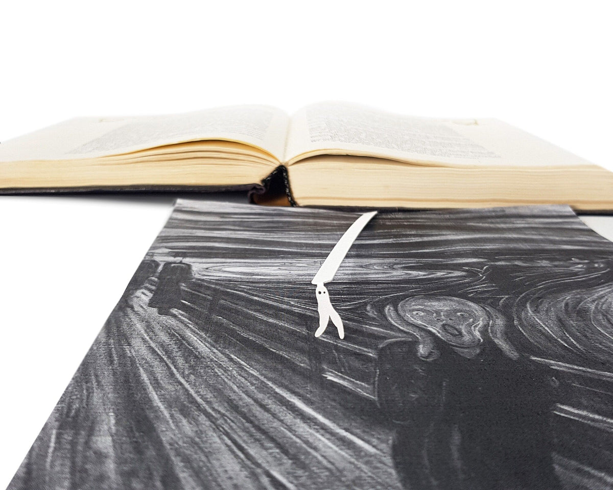 Nightcrawler metal bookmark in white marking a page in an illustrated book