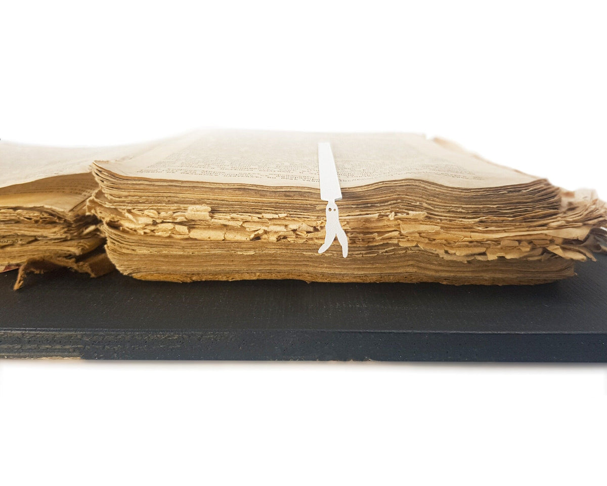 Nightcrawler metal bookmark in white clipped in a closed book, viewed from the side