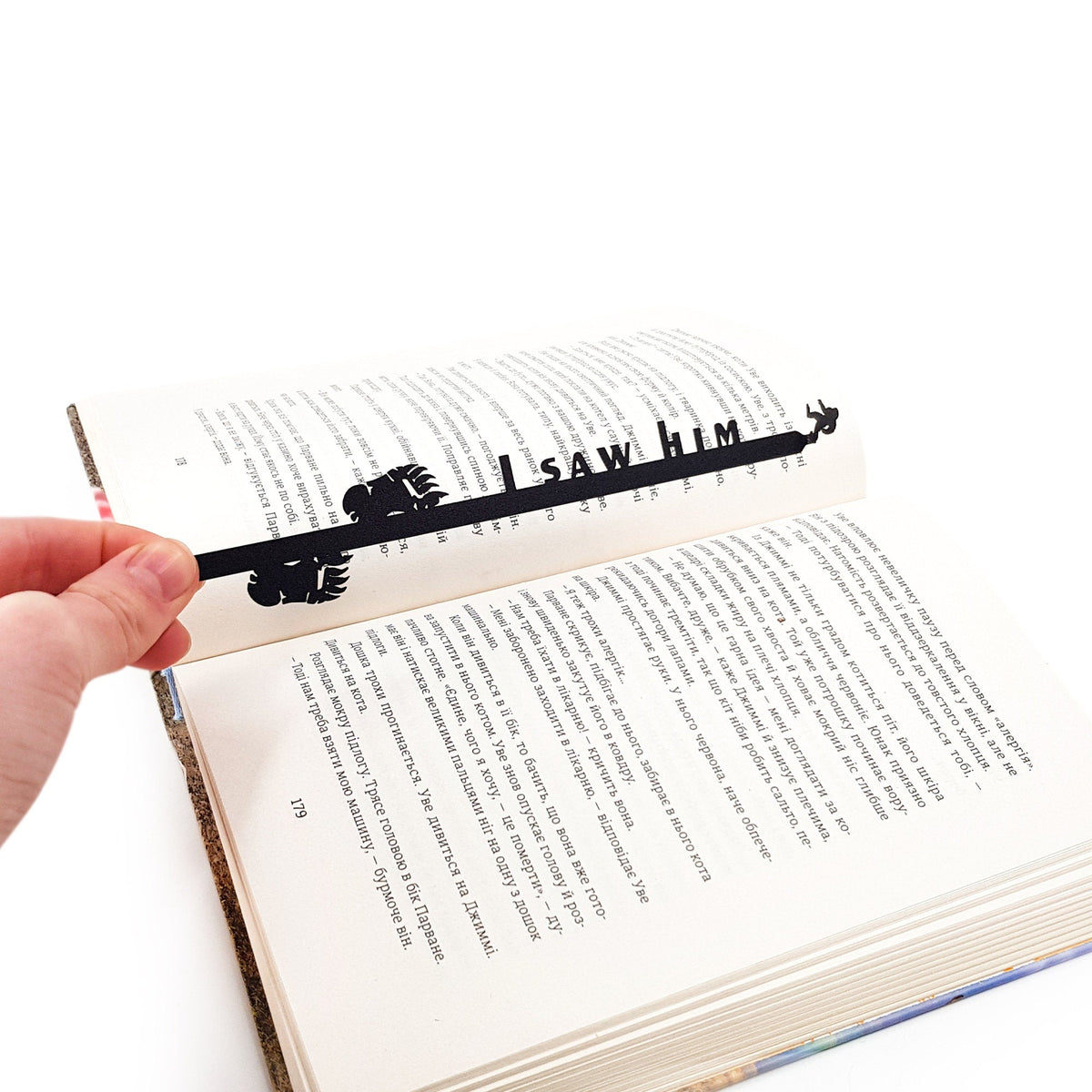 Bigfoot metal bookmark held in a hand above an open book