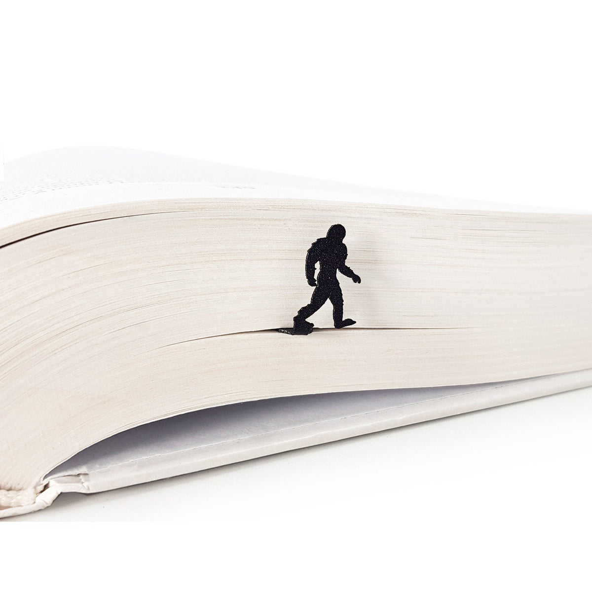 Bigfoot metal bookmark resting on the pages of an open book