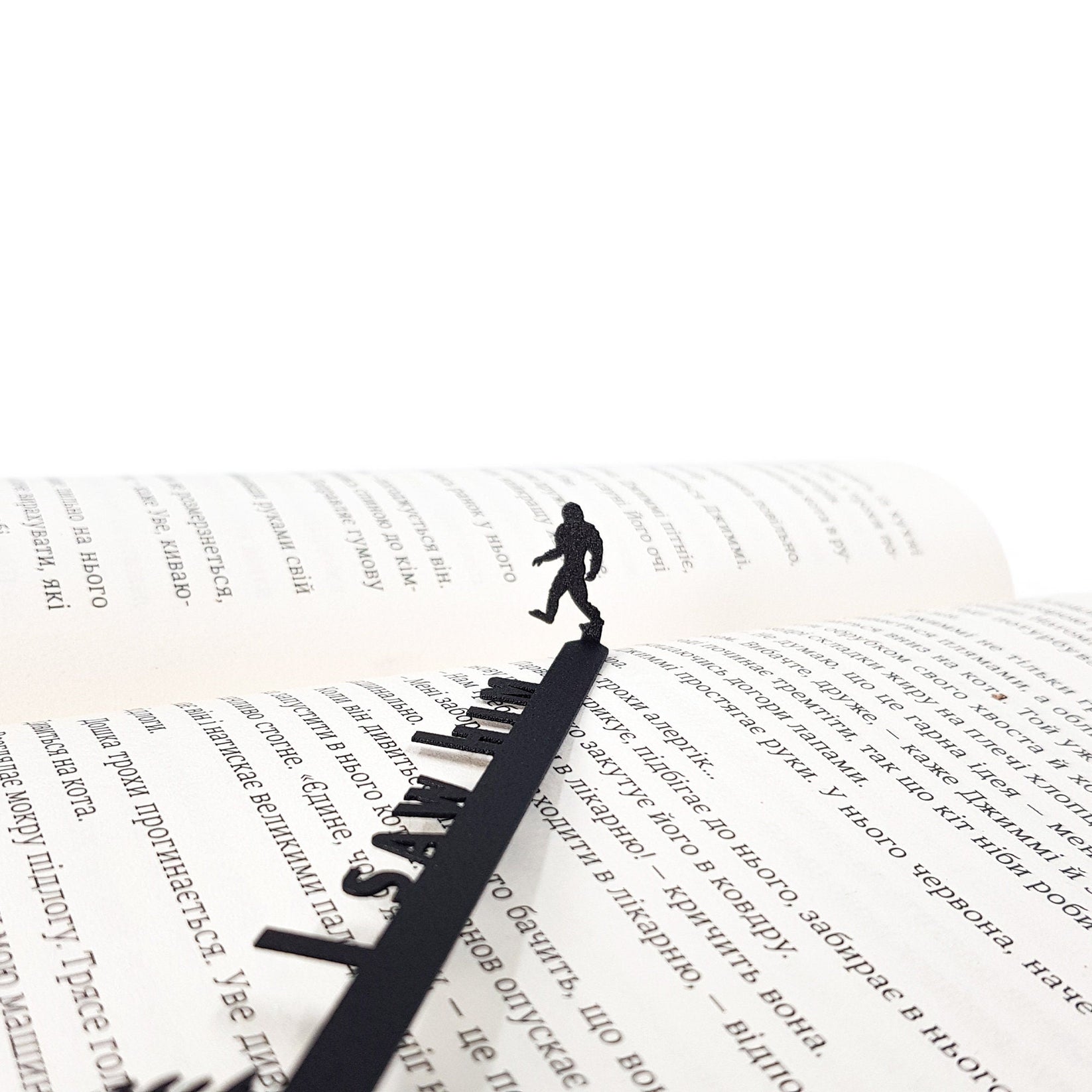 Bigfoot metal bookmark lying across the pages of an open book