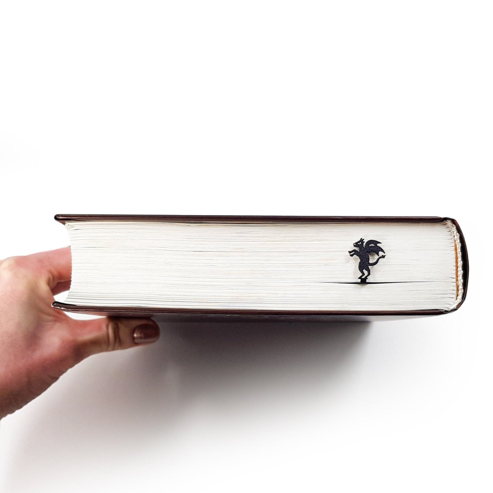 Monster Jersey Devil metal bookmark held up beside an open book