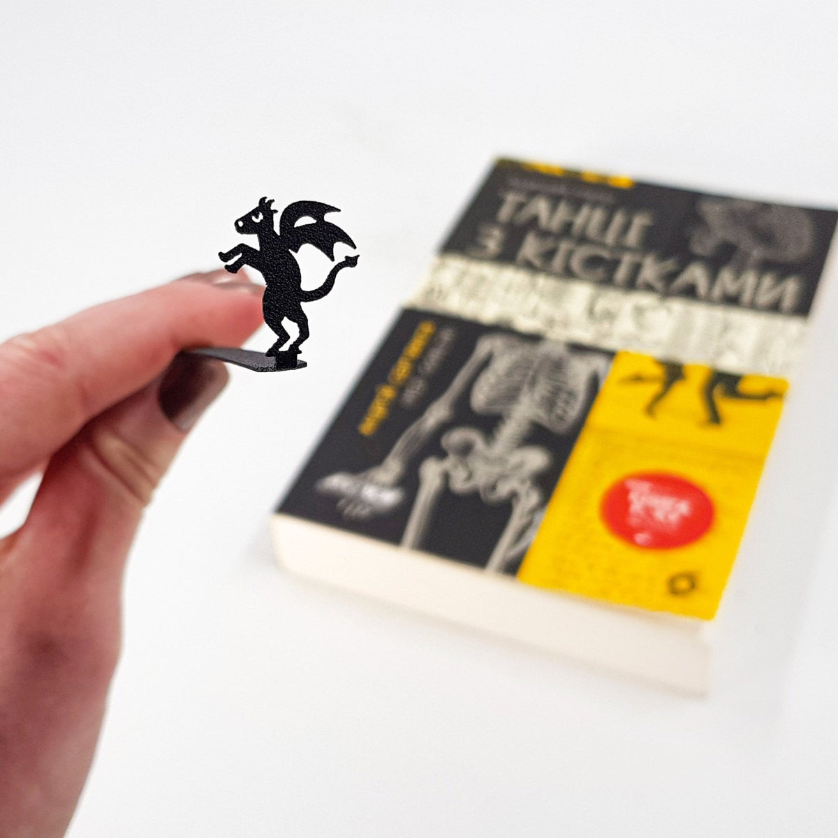 Monster Jersey Devil metal bookmark held in a hand above an open book