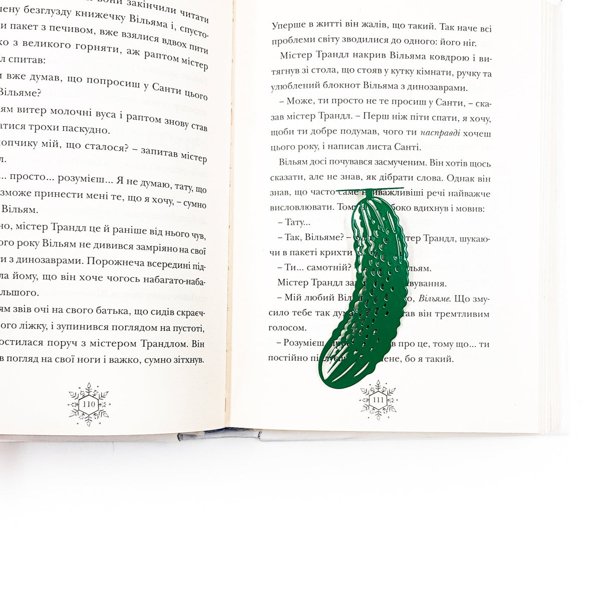 Cucumber metal bookmark in green marking a page in an open book