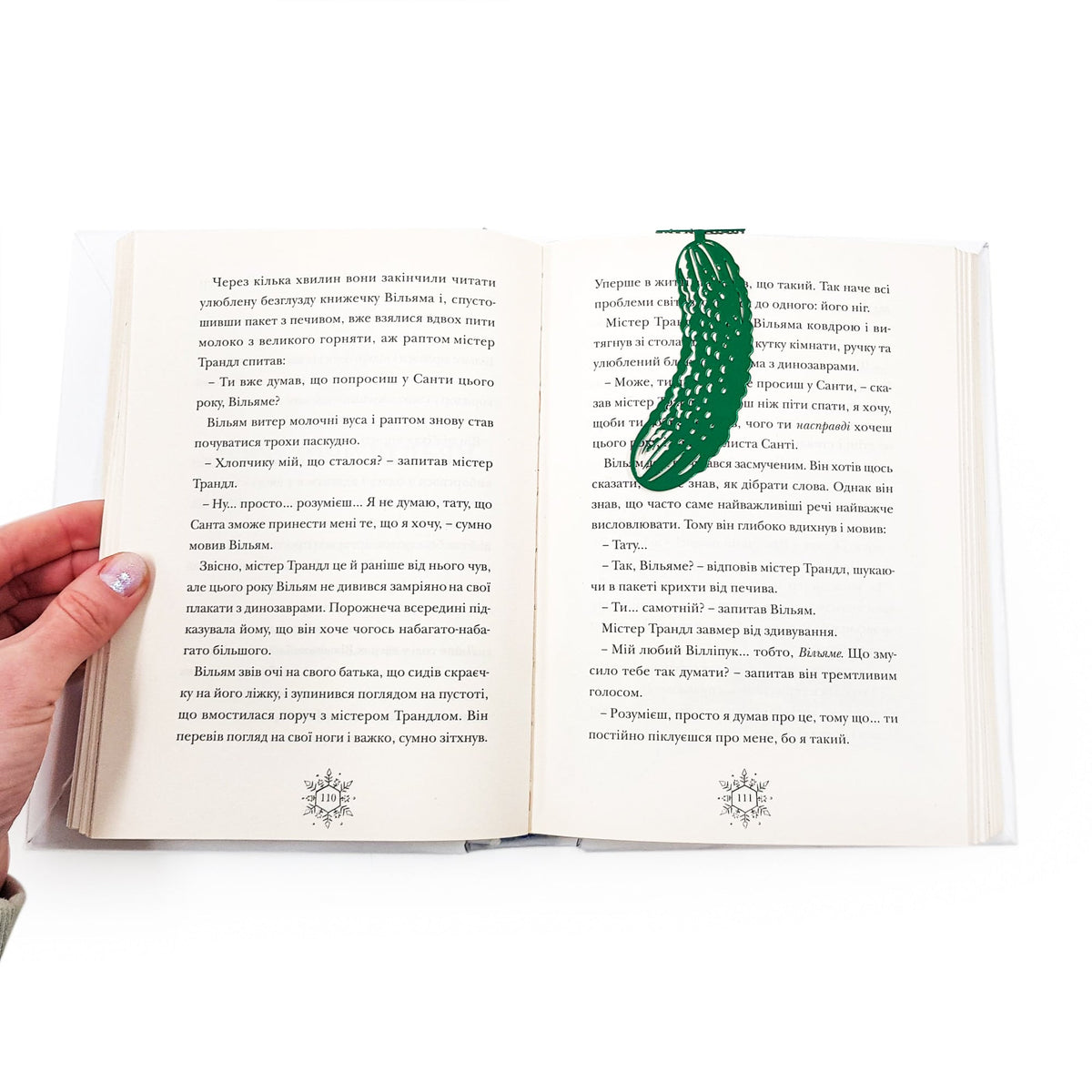 Cucumber metal bookmark in green resting on the pages of an open book