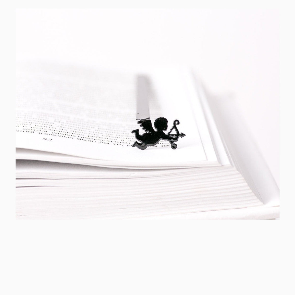 Cupid metal bookmark resting on the pages of an open book