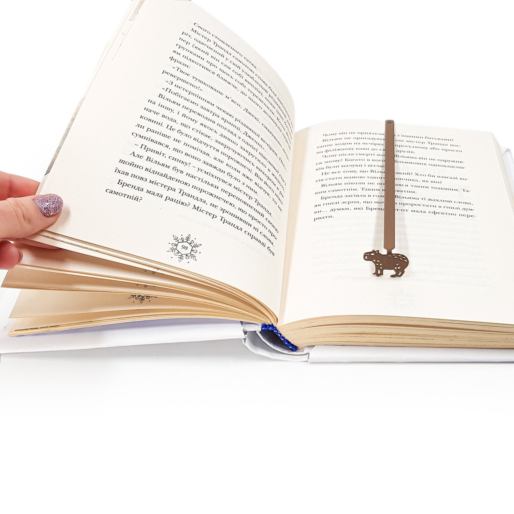 Capybara metal bookmark resting on the pages of an open book