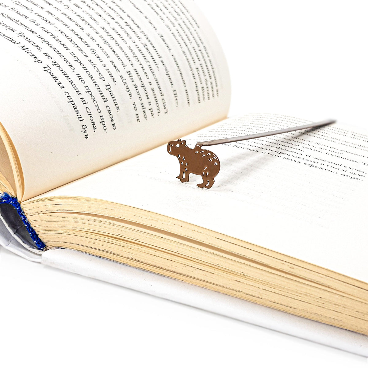 Capybara metal bookmark marking a page in an open book