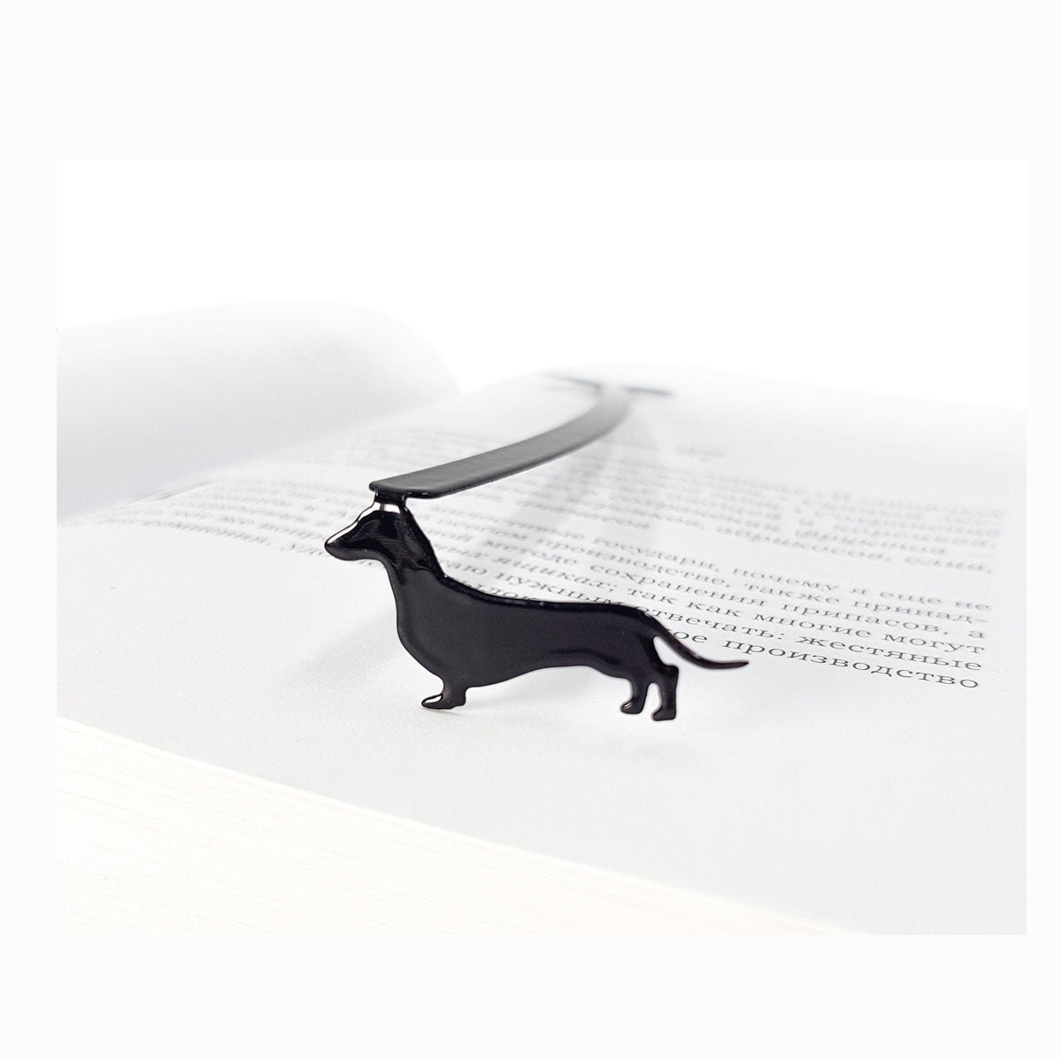Dachshund metal bookmark resting on the pages of an open book