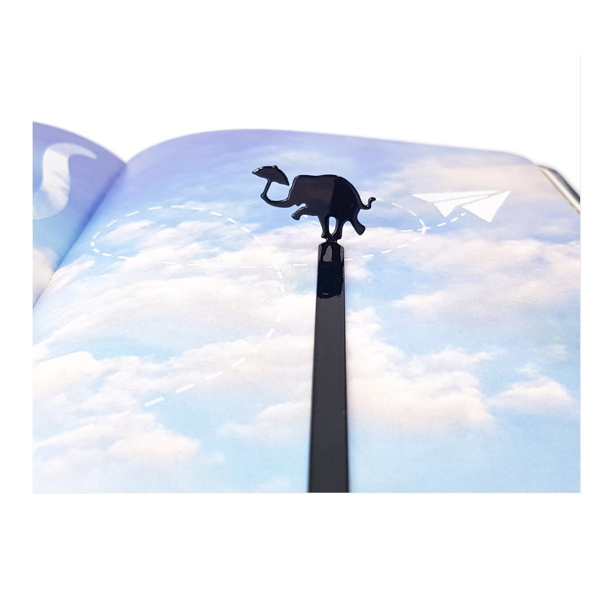Dancing Elephant metal bookmark marking a page in an illustrated book