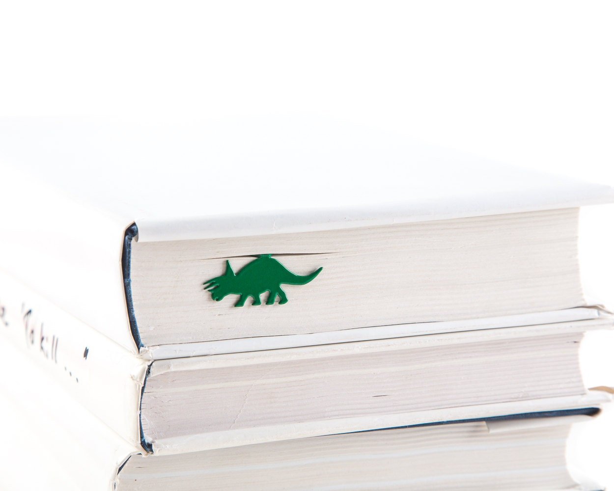 Dinosaur Trice raptor metal bookmark in green shown with a stack of books
