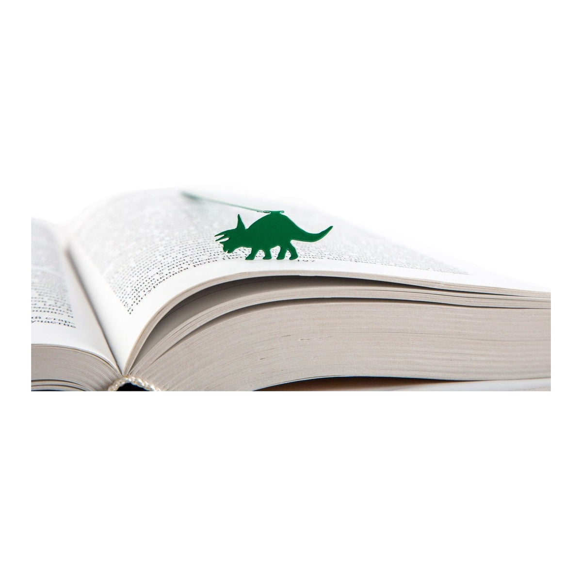 Dinosaur Trice raptor metal bookmark in green resting on the pages of an open book