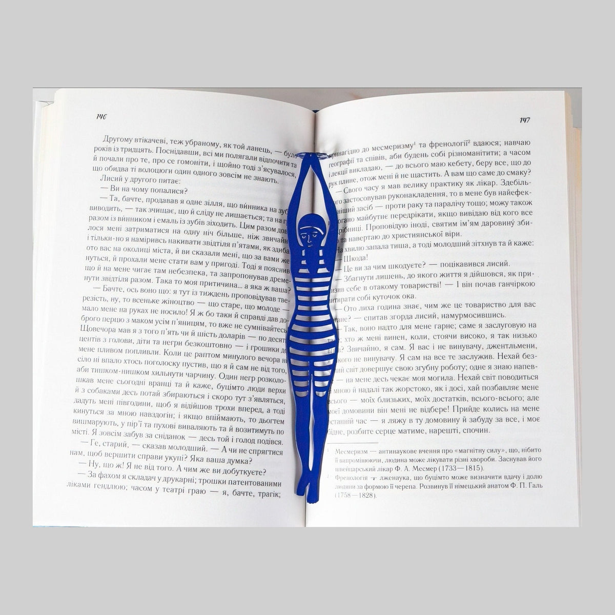 Diving Girl metal bookmark in blue resting on the pages of an open book