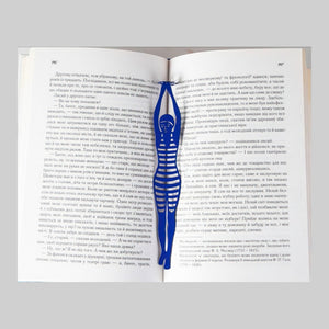 Diving Girl metal bookmark in blue resting on the pages of an open book