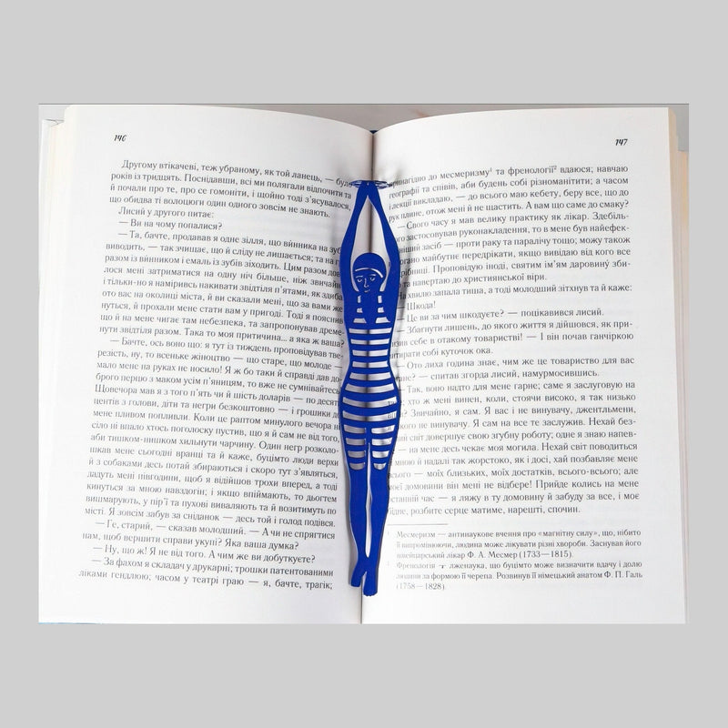 Diving Girl metal bookmark in blue resting on the pages of an open book