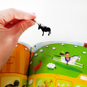 Hand holding black steel donkey bookmark above open children's farm picture book