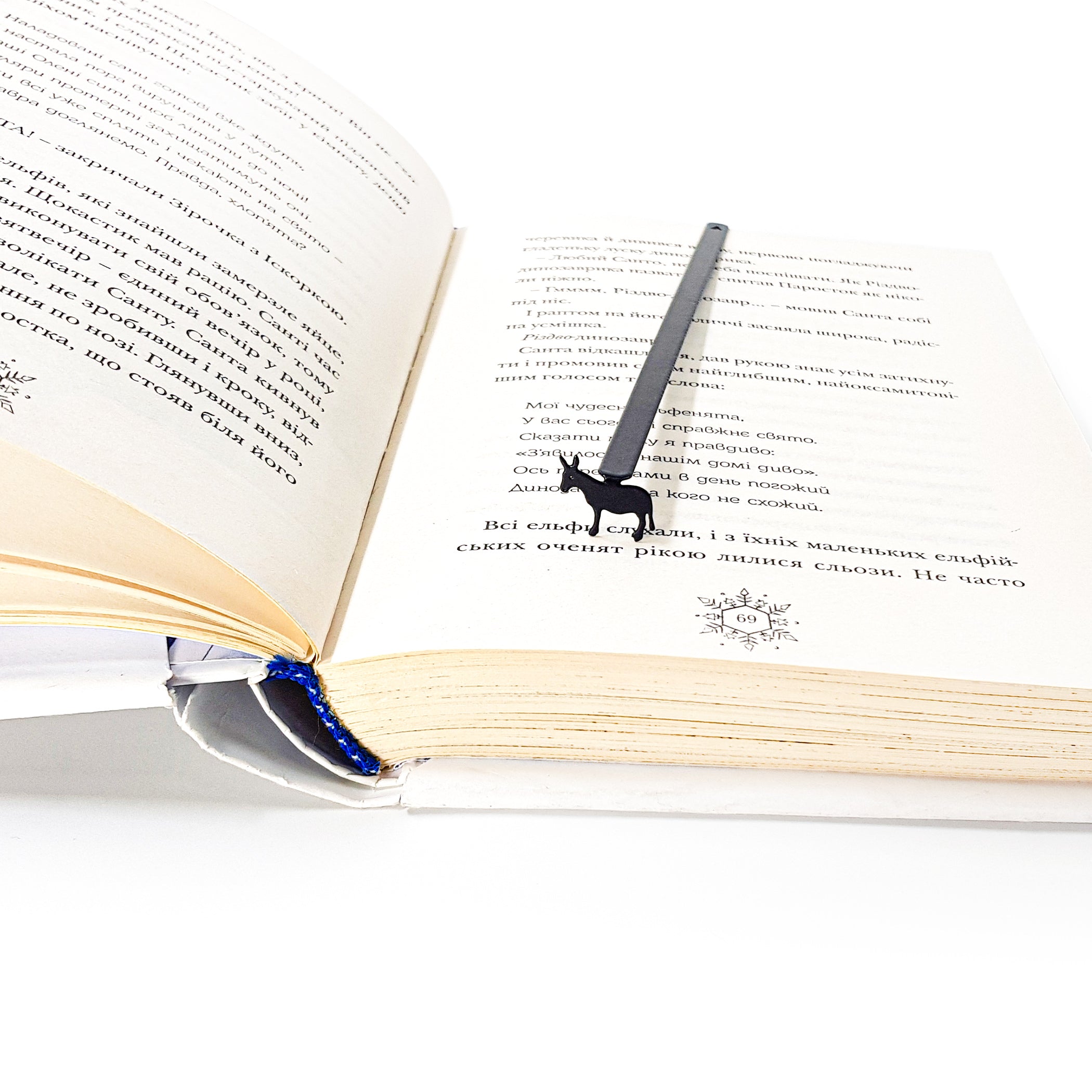 Donkey metal bookmark sitting upright inside open book with Ukrainian text pages
