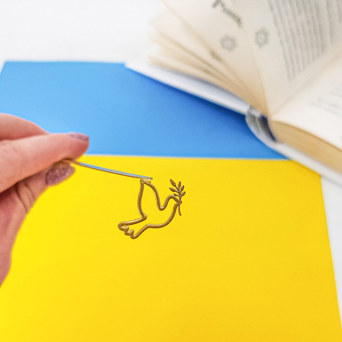 Dove of Peace metal bookmark in gold on a coloured background