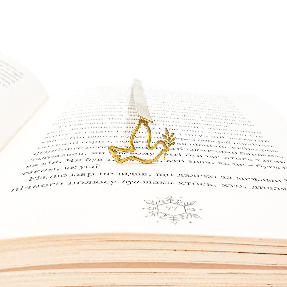 Dove of Peace metal bookmark in gold set into the gutter of an open book