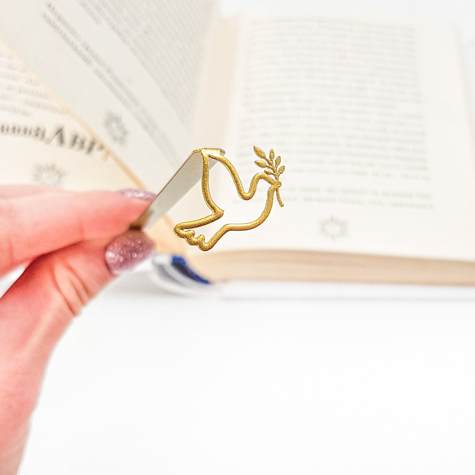 Dove of Peace metal bookmark in gold held in a hand to show its size