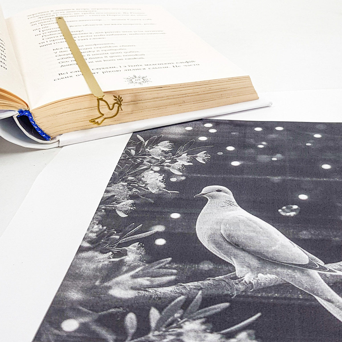 Dove of Peace metal bookmark in gold marking a page in an open book