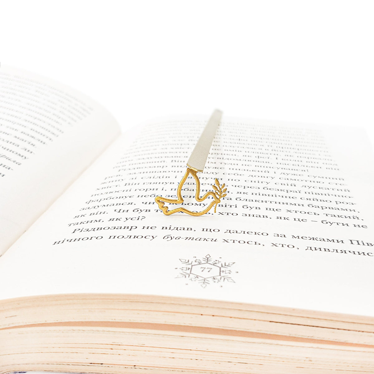 Dove of Peace metal bookmark in gold lying across the pages of an open book