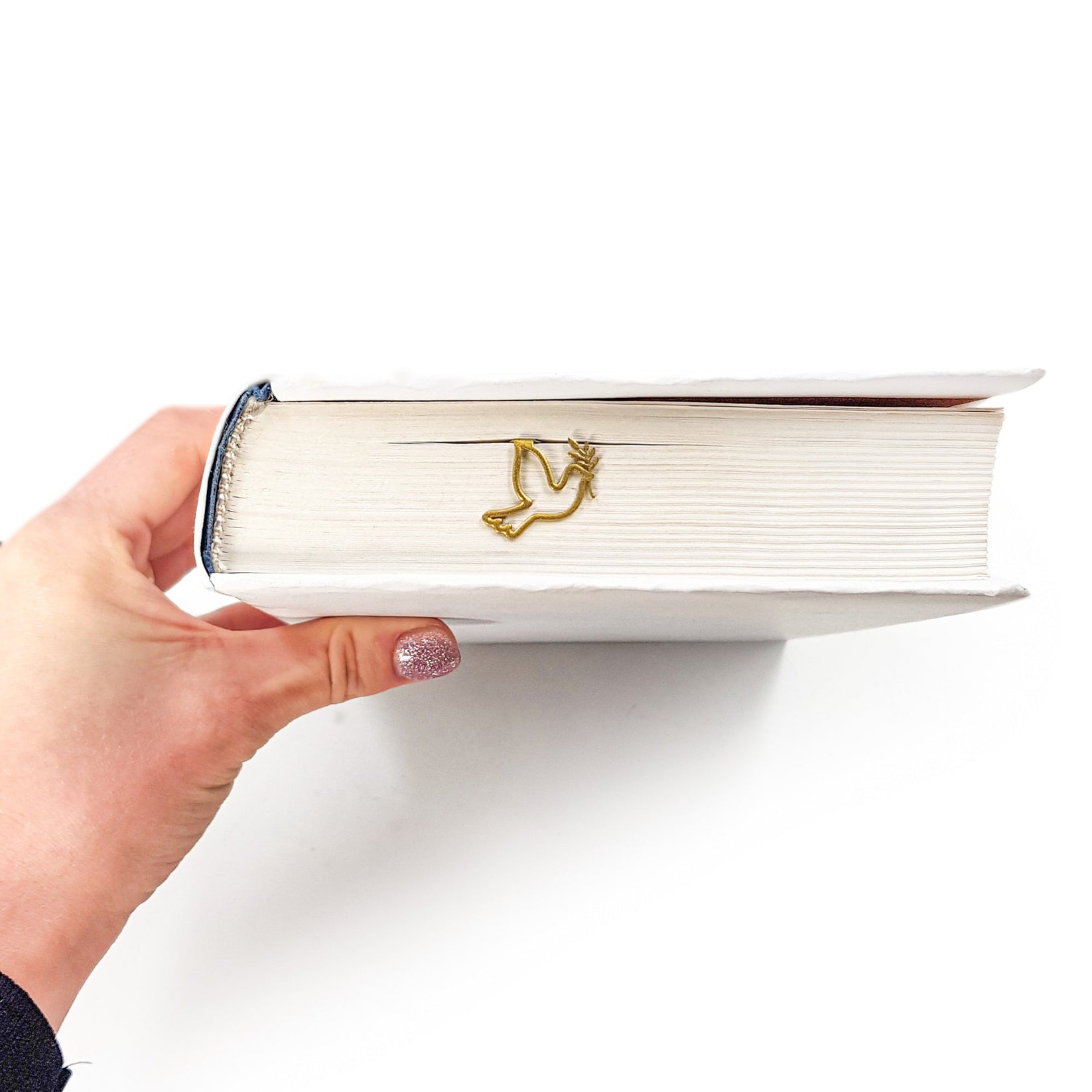 Dove of Peace metal bookmark in gold in a closed book, only its top showing above the pages