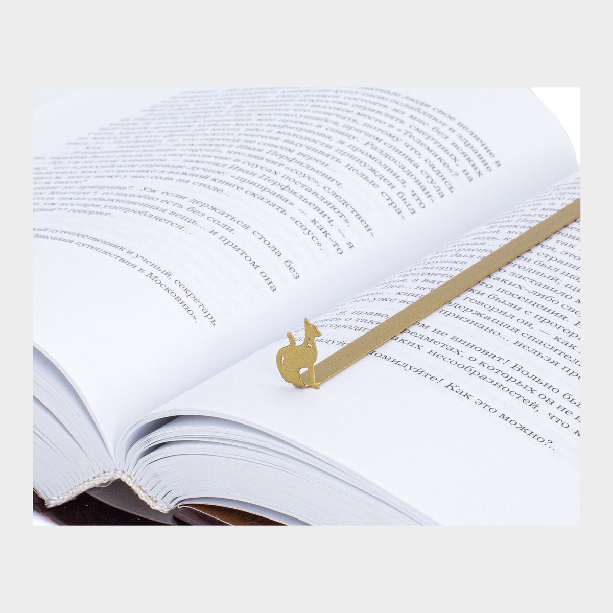 Egyptian Cat metal bookmark in gold resting on the pages of an open book