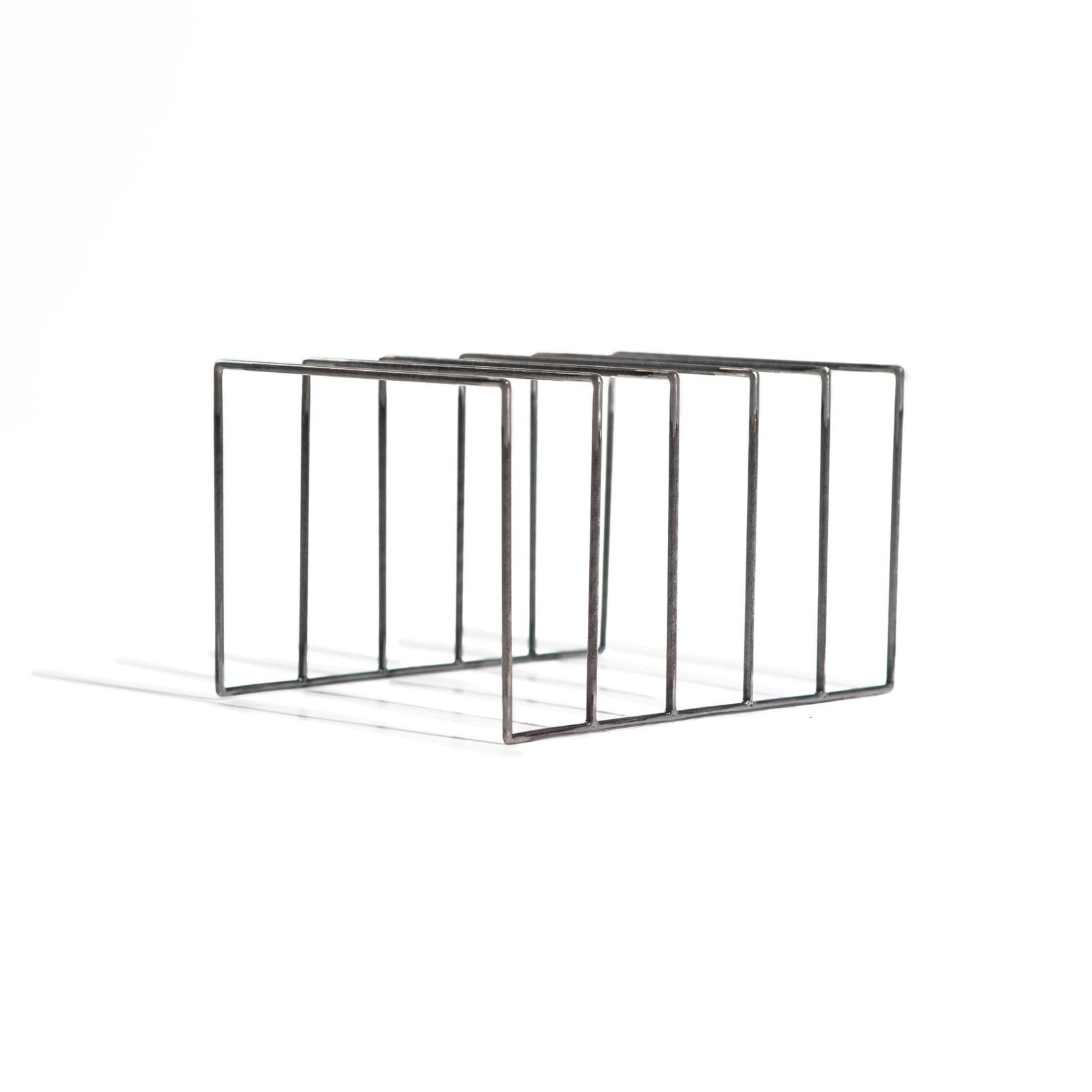 Minimalist black metal vinyl record holder with five evenly spaced slots, photographed on a white background. The industrial-style stand features a raw steel finish and clean geometric lines, designed to display and organize LP records.