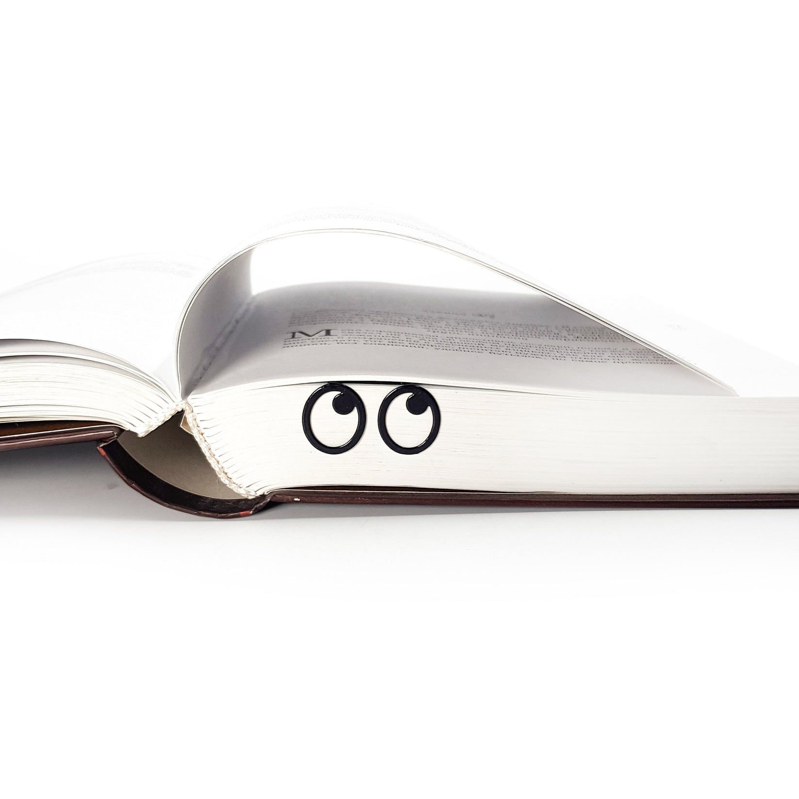 Eyes Glasses metal bookmark lying across the pages of an open book