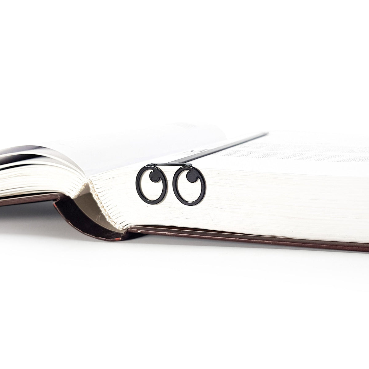 Eyes Glasses metal bookmark set into the gutter of an open book