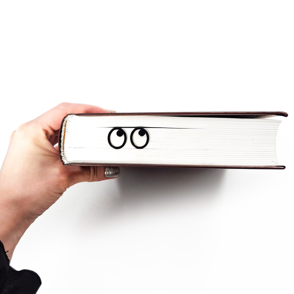Eyes Glasses metal bookmark in a closed book, only its top showing above the pages