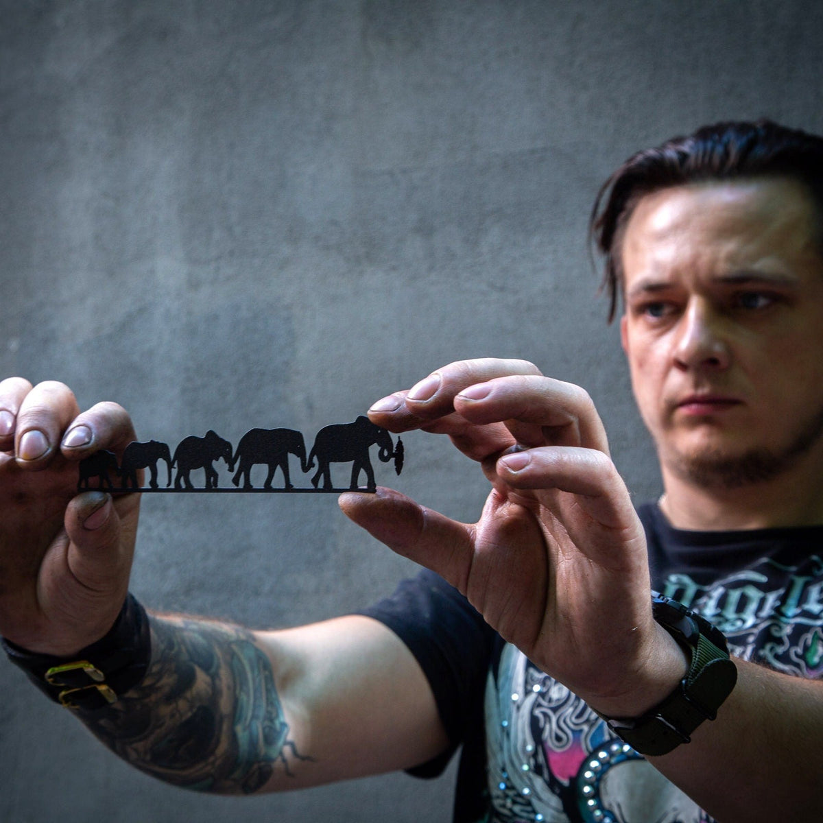 Family of Elephants metal bookmark held in a hand above an open book
