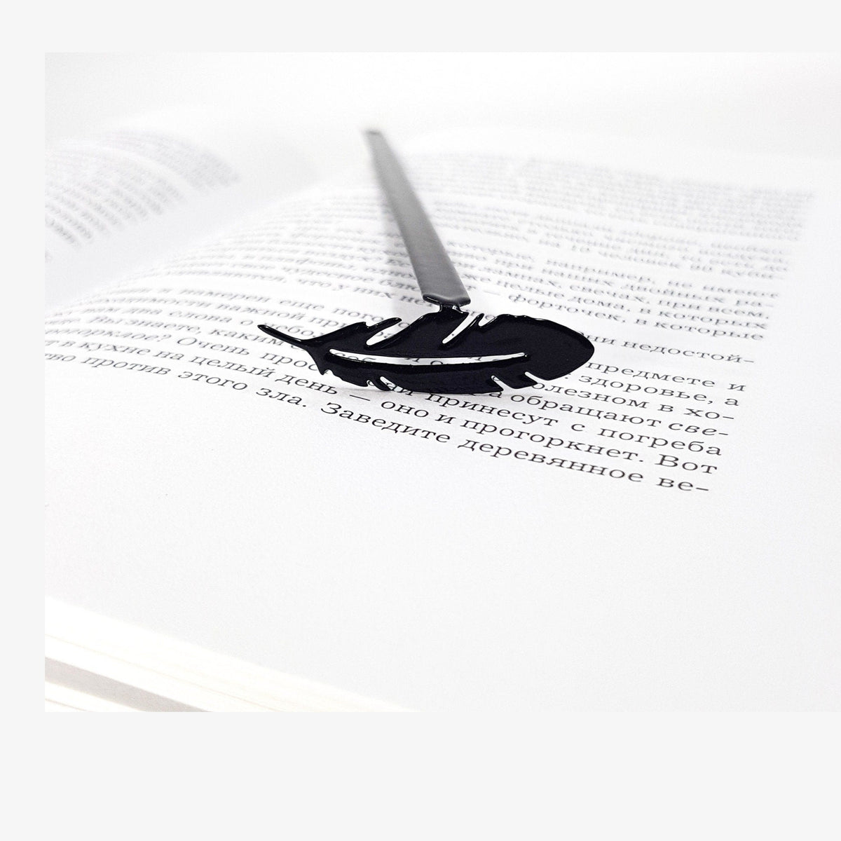 Feather metal bookmark resting on the pages of an open book