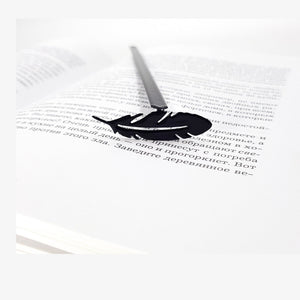 Feather metal bookmark resting on the pages of an open book