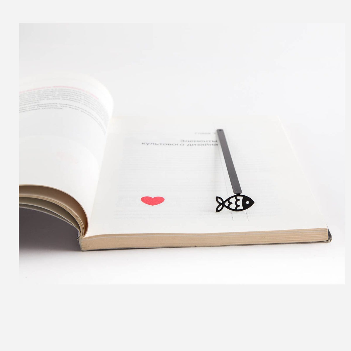 Fish metal bookmark resting on the pages of an open book