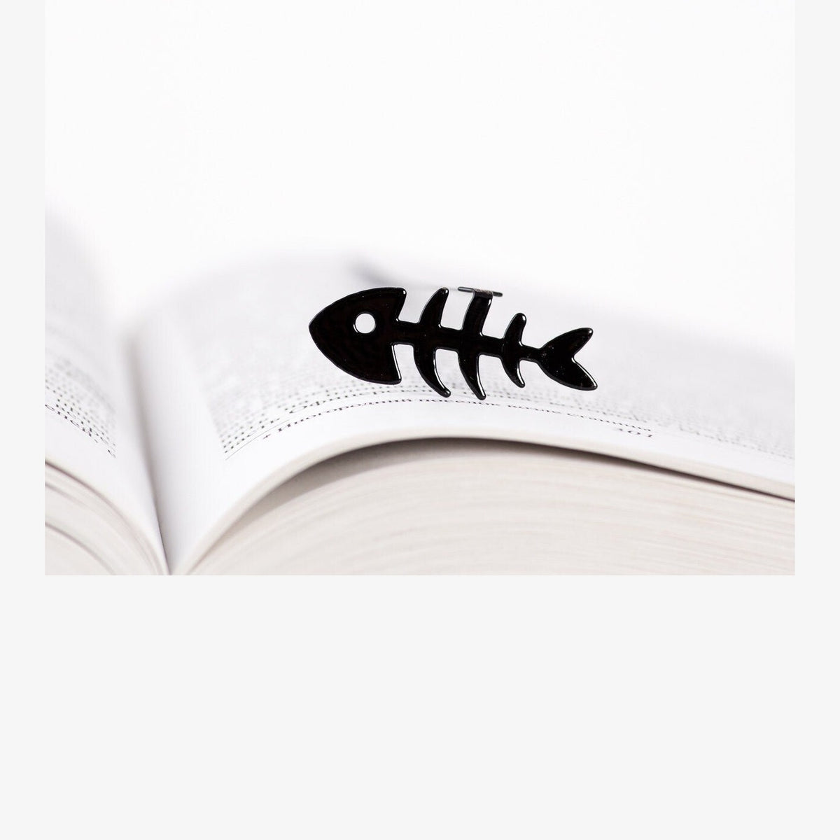 Fishbone metal bookmark resting on the pages of an open book