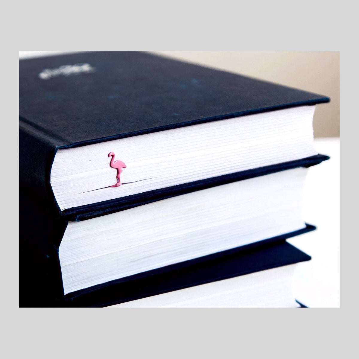 Flamingo metal bookmark in red shown with a stack of books