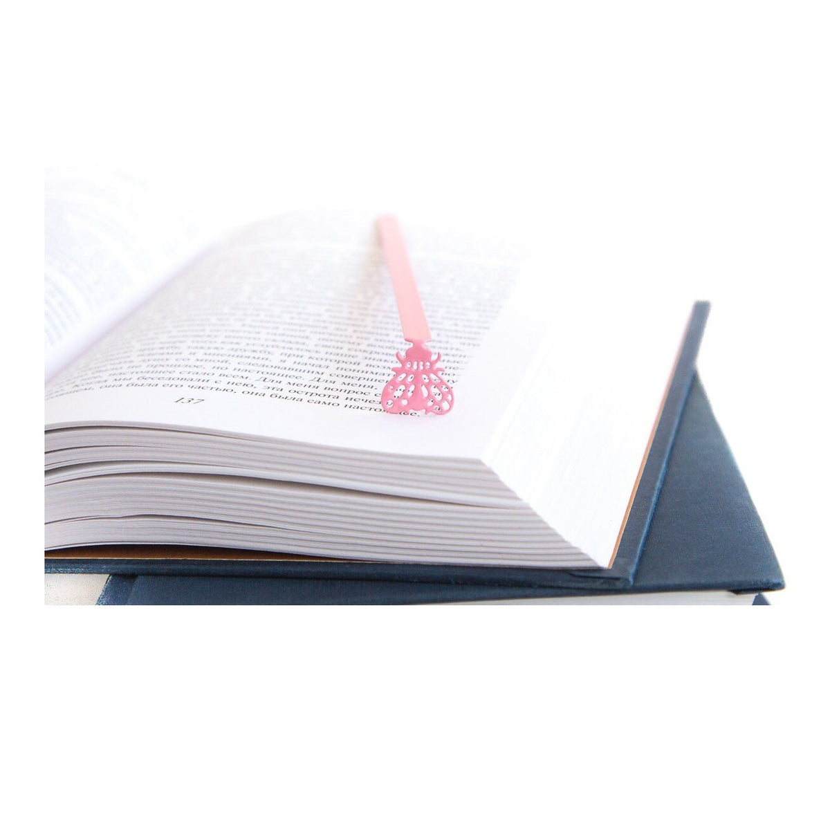 Fly metal bookmark in red resting on the pages of an open book