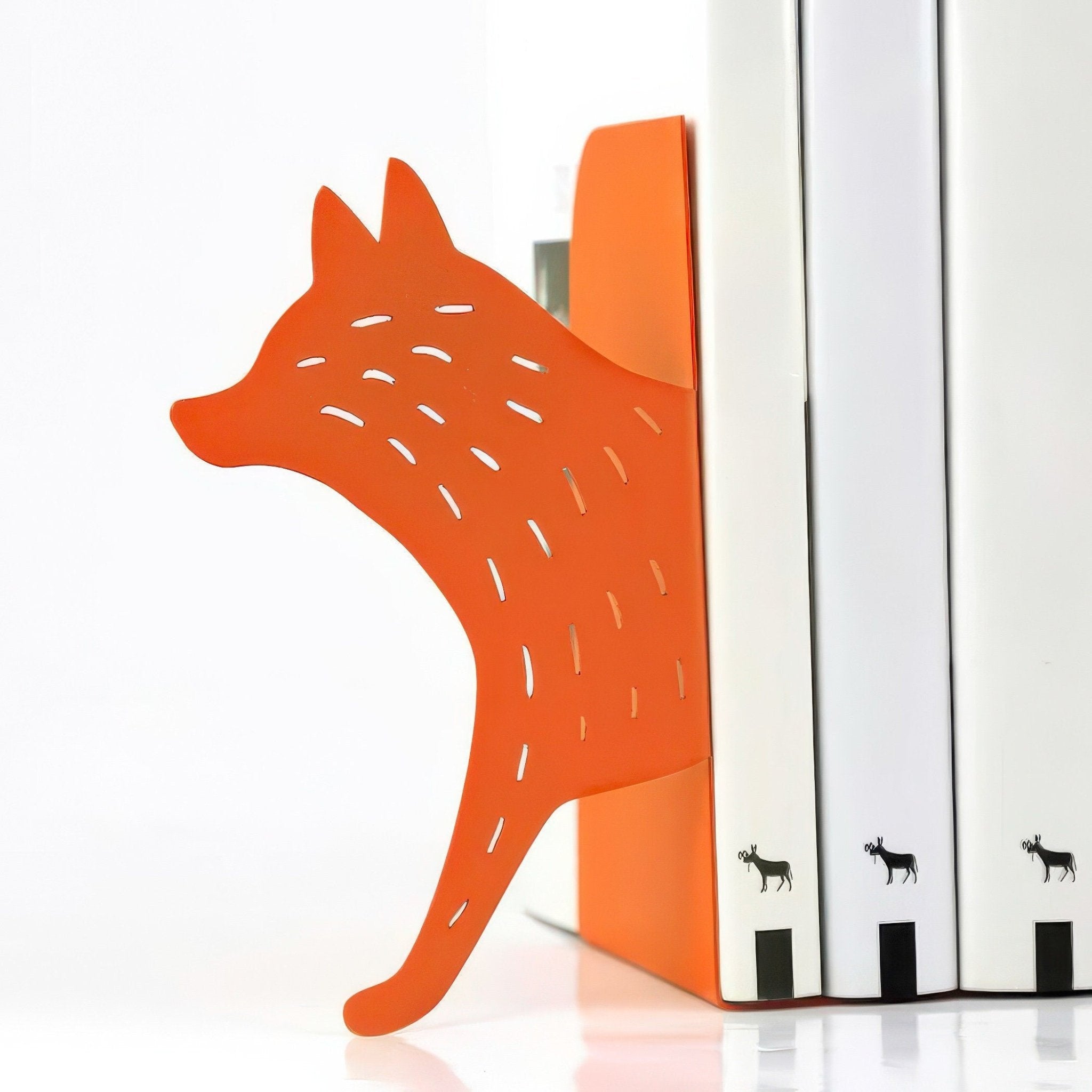 Close-up of orange fox metal bookends holding white books
