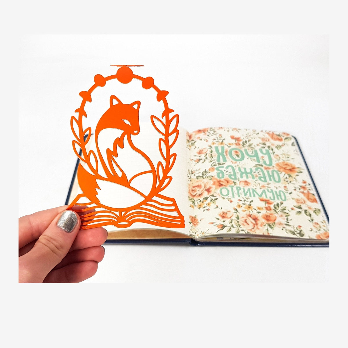 Fox on the Book metal bookmark held in a hand above an open book