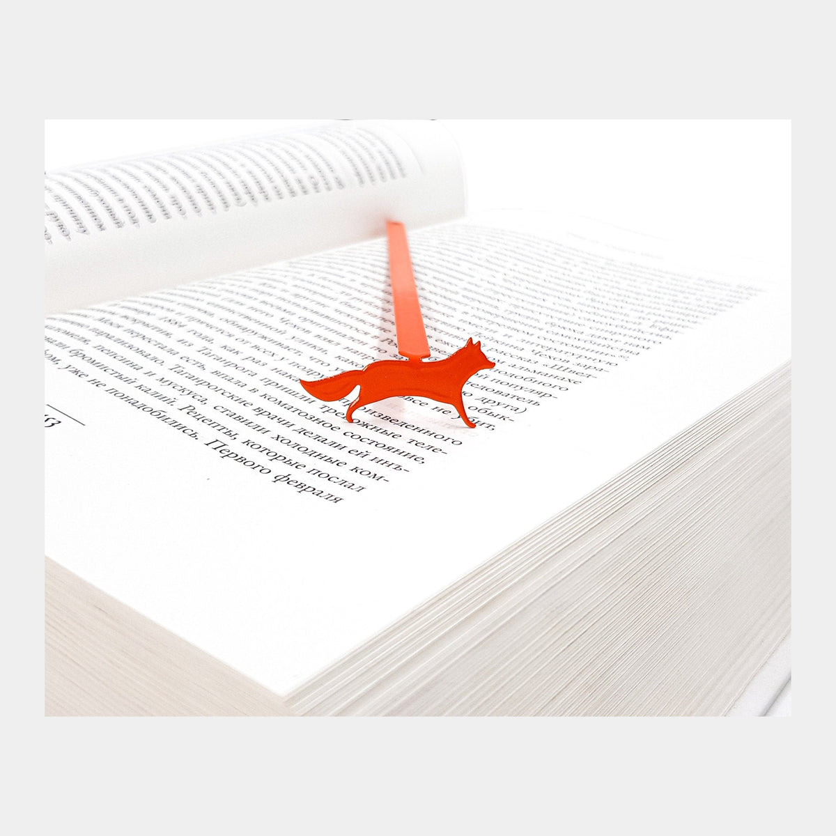 Fox on the Run metal bookmark in red resting on the pages of an open book
