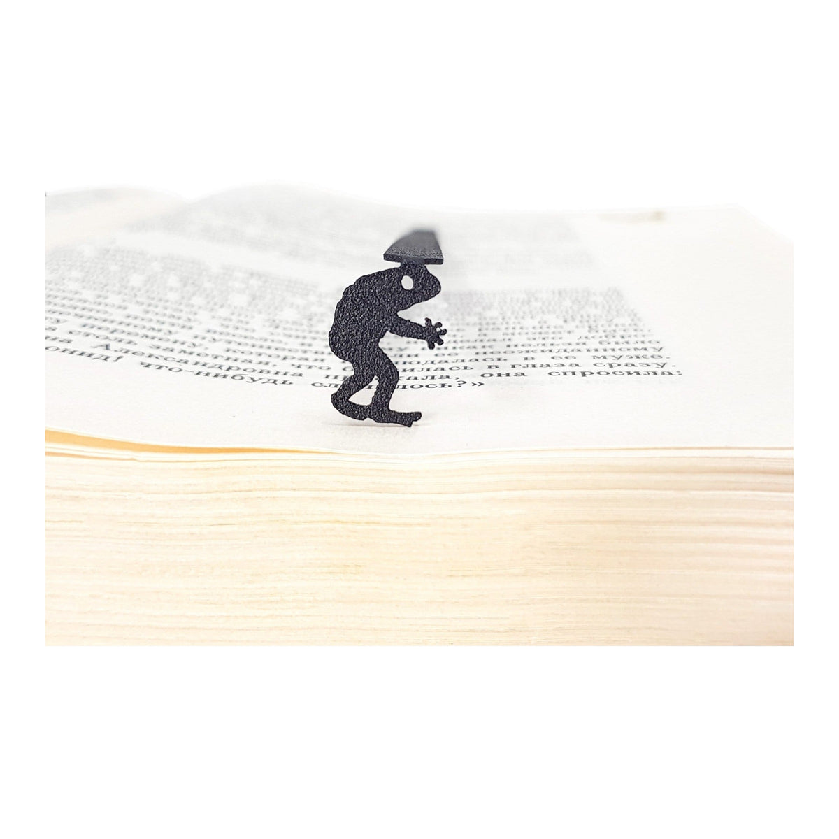 Frogman metal bookmark resting on the pages of an open book