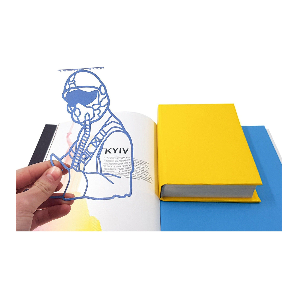 Ghost of Kyiv metal bookmark held in a hand above an open book
