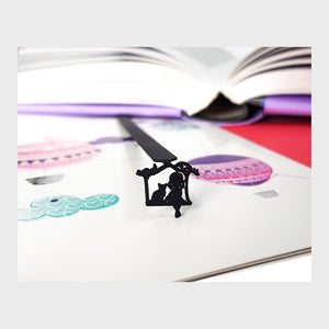 Girl Sitting with the Cat metal bookmark resting on the pages of an open book