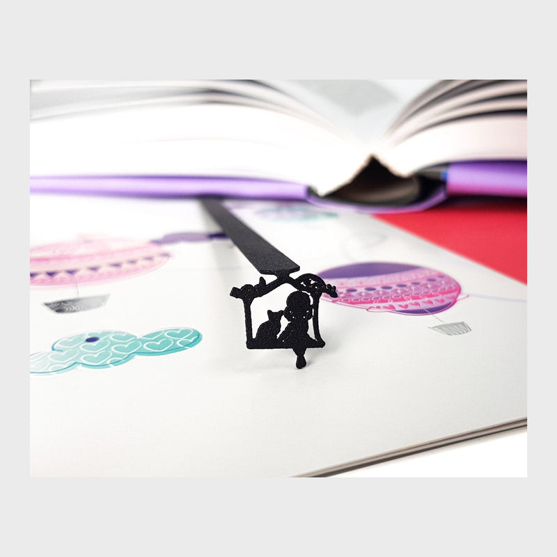 Girl Sitting with the Cat metal bookmark resting on the pages of an open book