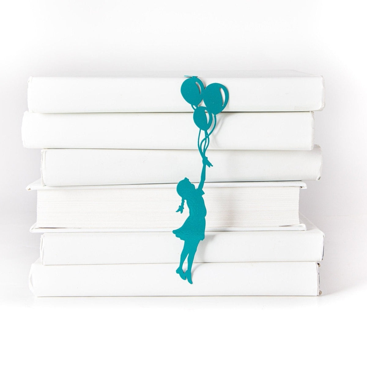 Girl with Balloons metal bookmark in green shown with a stack of books